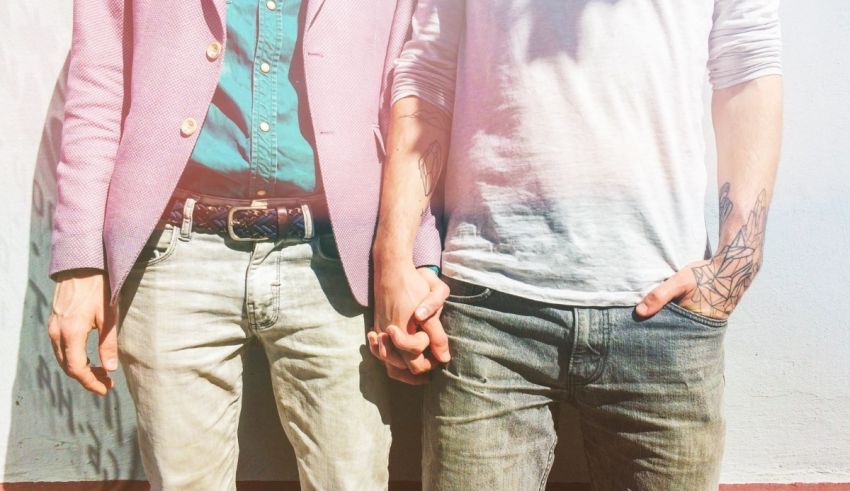 Two men holding hands in front of a wall.