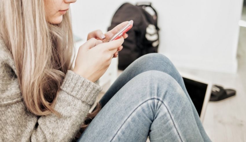 A woman sitting on the floor looking at her phone.