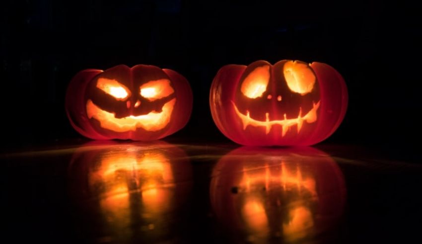 Two carved pumpkins lit up in the dark.