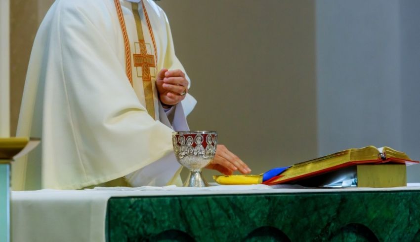 A priest is holding a book in front of him.