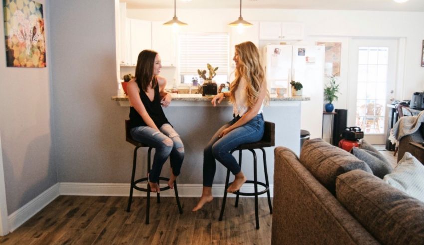 Two women sitting on stools in a living room.