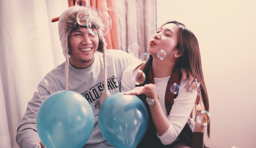 A man and woman holding soap bubbles and balloons.