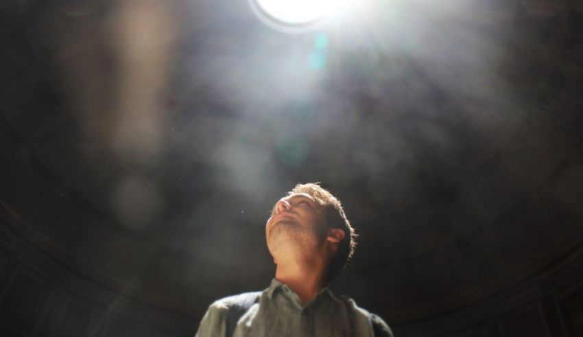 A man looking up at the sun through a dome.