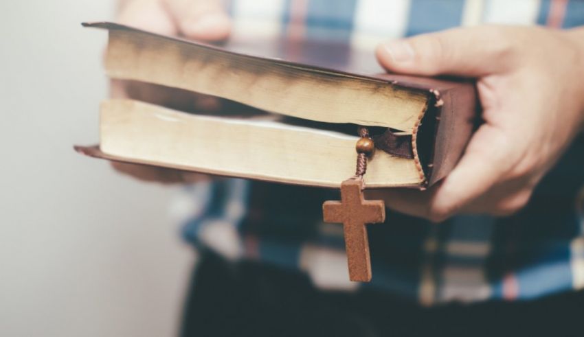 A man is holding a bible with a cross on it.