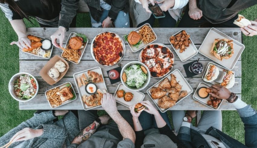 A group of people eating food at a picnic table.