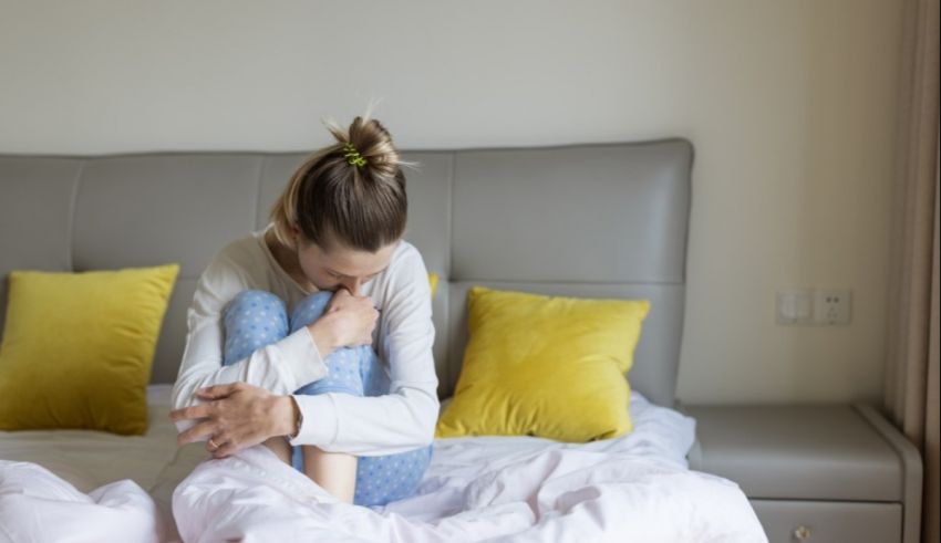 A woman sitting on a bed with her legs crossed.