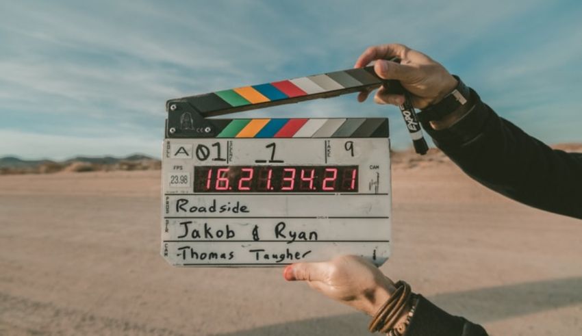 A person holding up a clapper board in the desert.