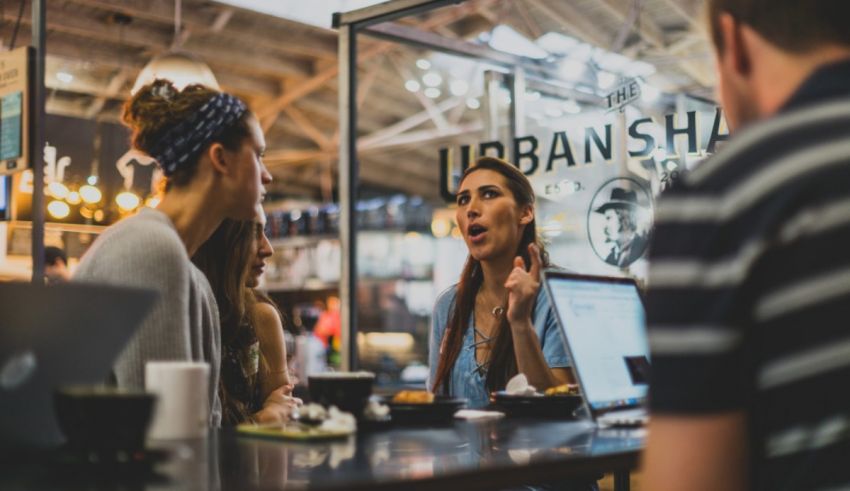 A group of people sitting at a table in a coffee shop.