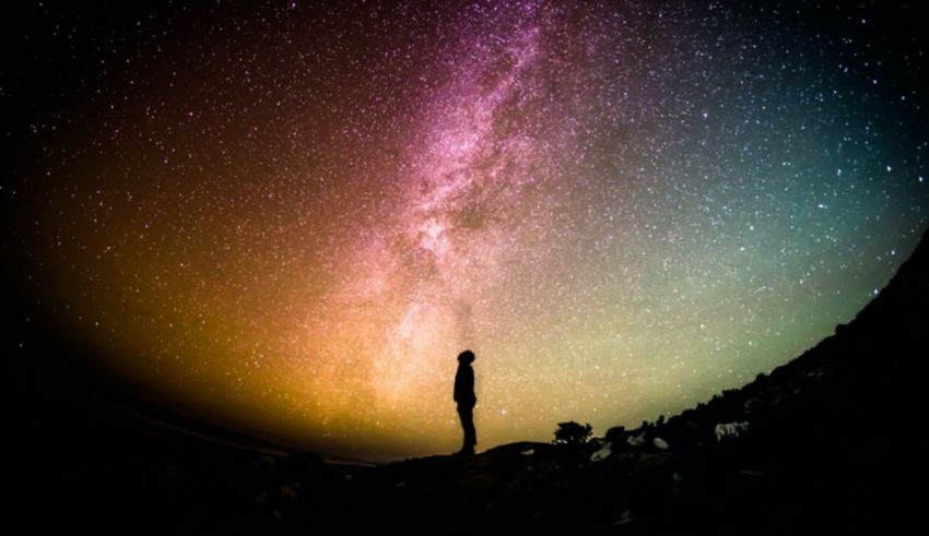 A person standing on a hill with stars in the sky.