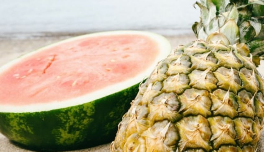 A watermelon and a slice of watermelon on the sand.