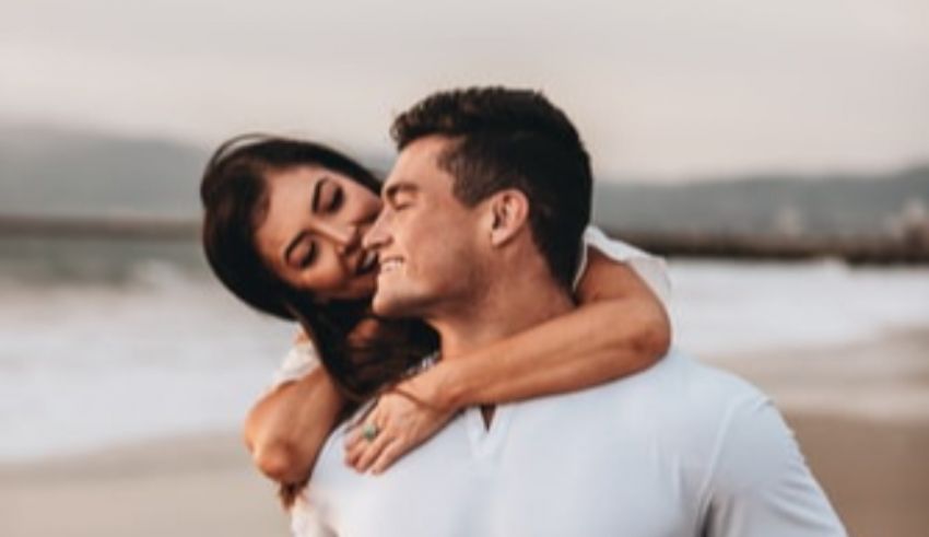 A man and woman hugging on the beach.