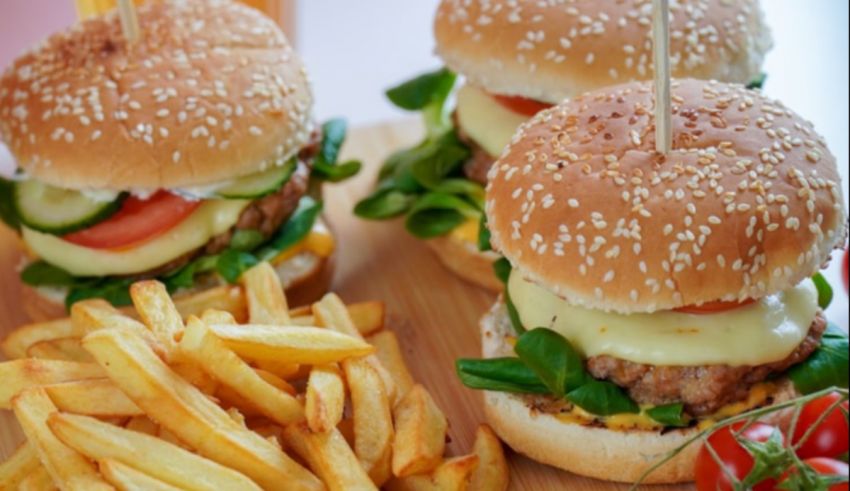 Burgers and fries on a wooden cutting board.