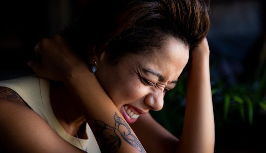 A woman with a tattoo on her arm is laughing.