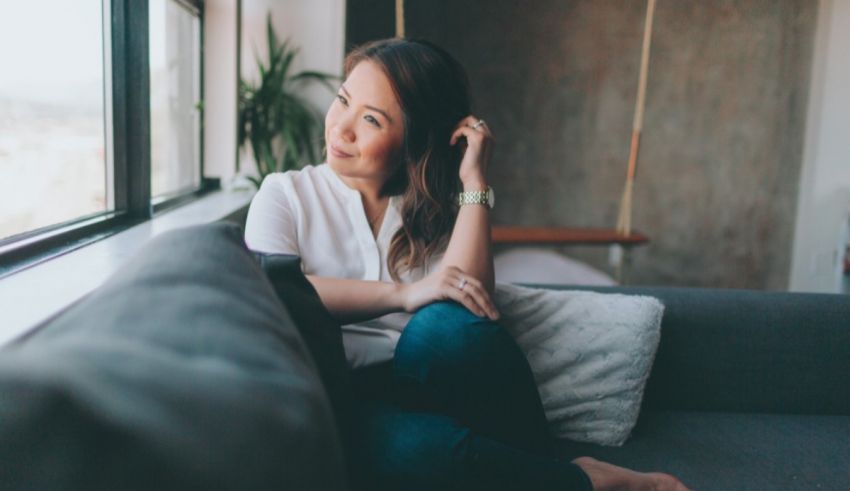 A woman sitting on a couch looking out a window.