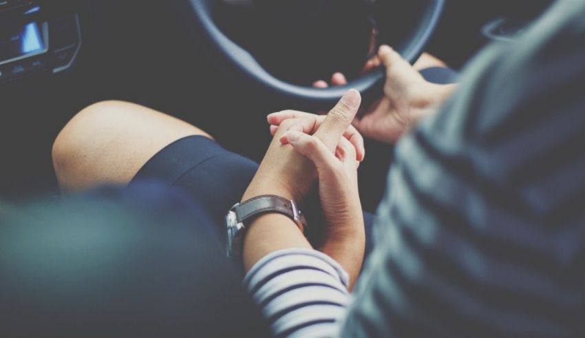 A woman is sitting in a car with her hands on the steering wheel.