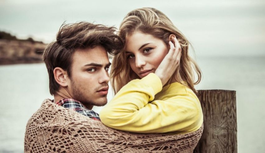 A young man and woman hugging near the ocean.