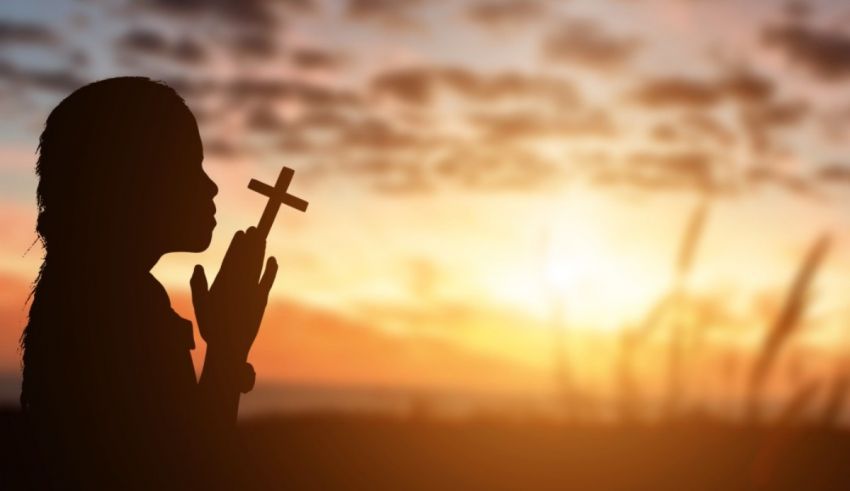 A silhouette of a child holding a cross.