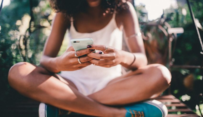 A woman sitting on a swing using her cell phone.