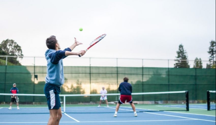 A group of people playing tennis on a tennis court.