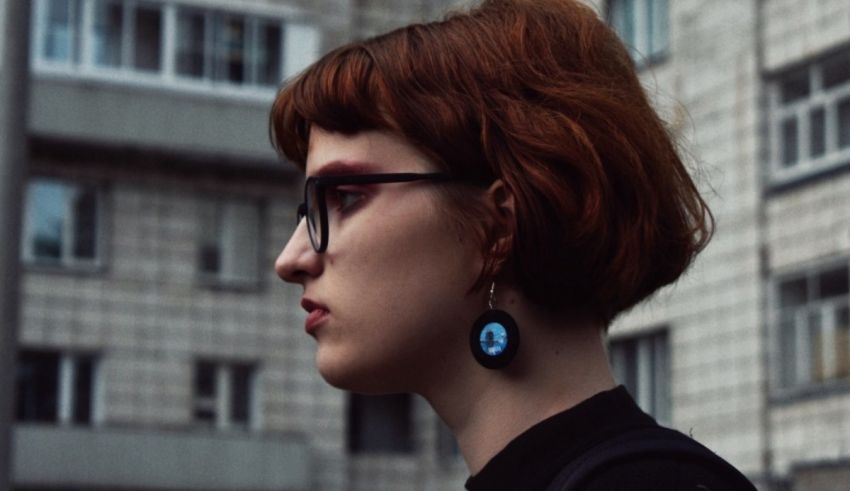 A woman wearing glasses and a blue earring.