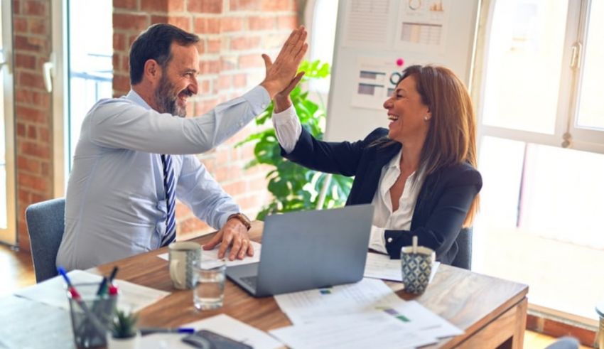 Two business people giving each other high fives in an office.