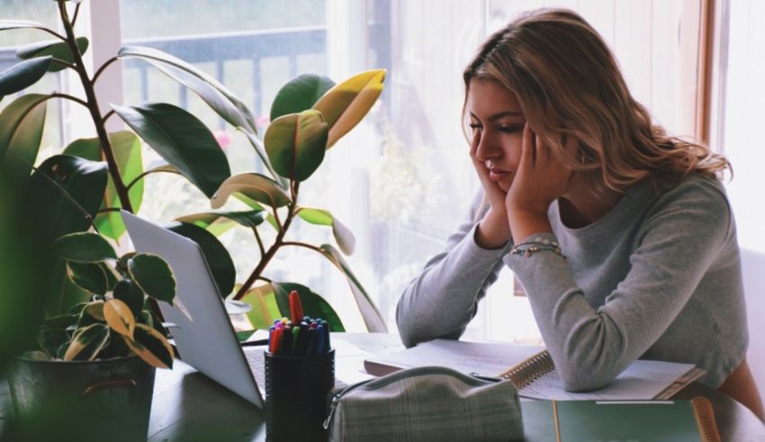 A woman sitting at a desk with her head on her face.