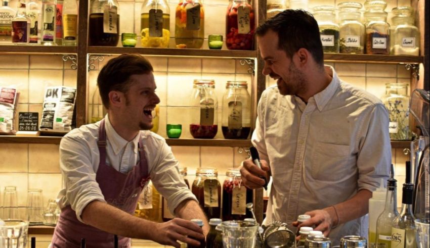 Two men in aprons laughing at each other.