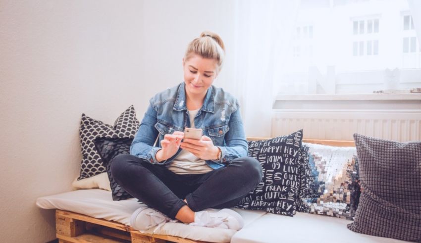 A woman sitting on a couch using her cell phone.