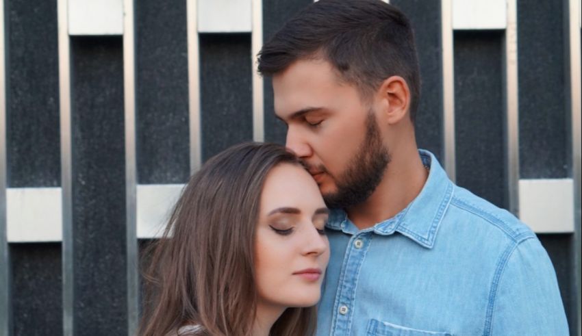 A man and woman hugging in front of a fence.