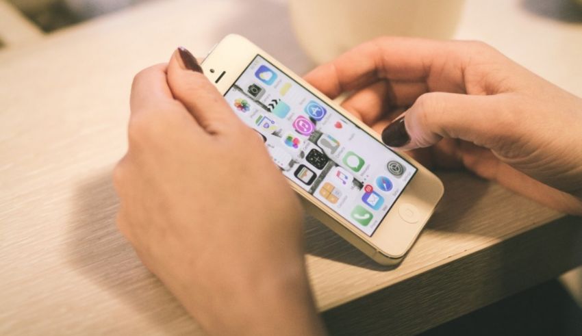 A woman is using an iphone on a table.