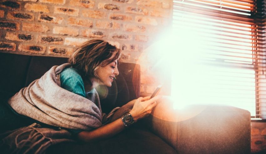 A woman sitting on a couch looking at a phone.
