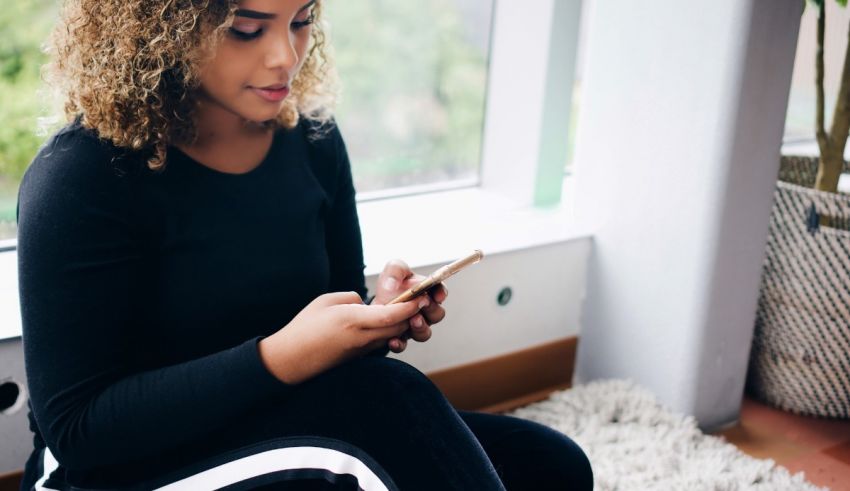 A woman sitting on a chair looking at her cell phone.