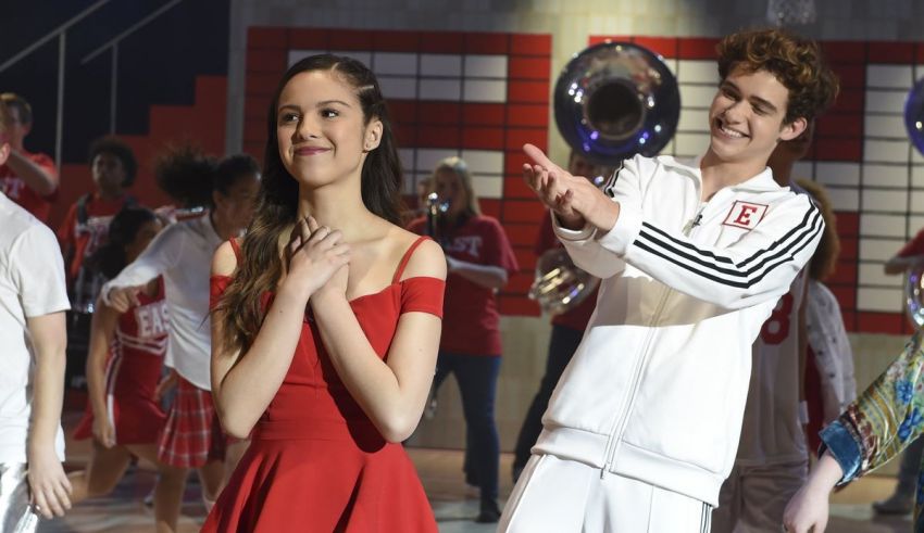 A group of people in a red dress are dancing on a stage.