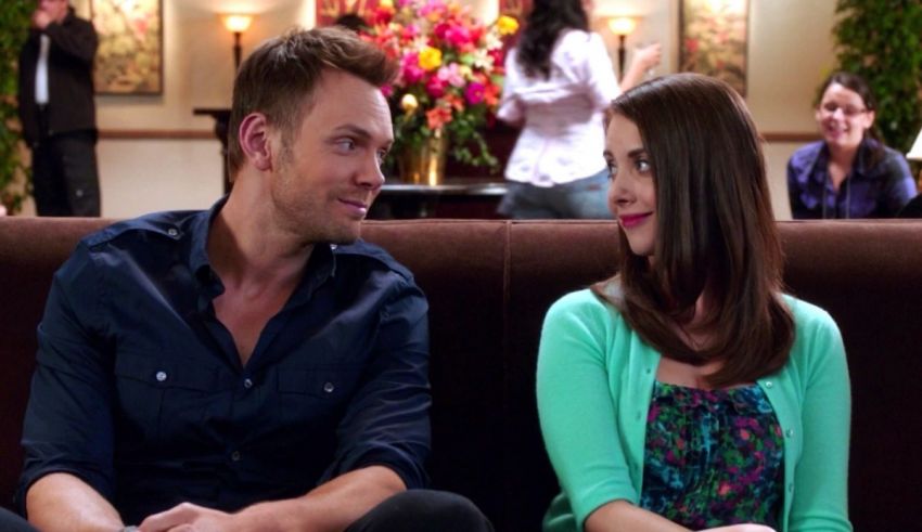 A man and woman sitting on a couch looking at each other.