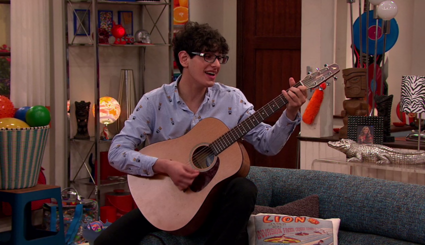 A man sitting on a couch playing a guitar.