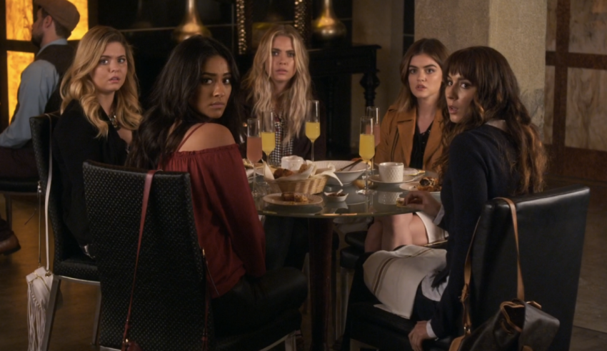 A group of girls sitting around a table in a restaurant.