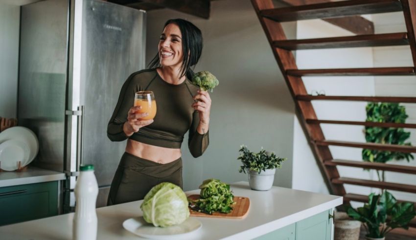A woman is standing in front of a kitchen with a glass of juice.