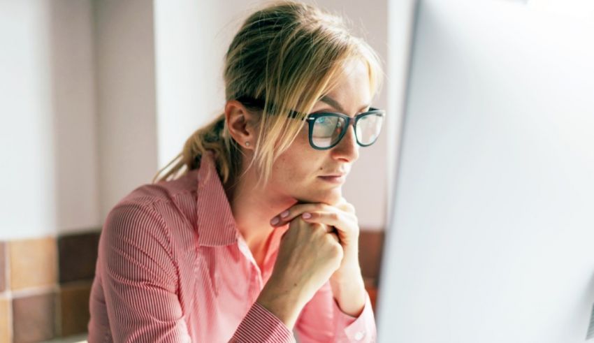 A woman wearing glasses is looking at a computer screen.