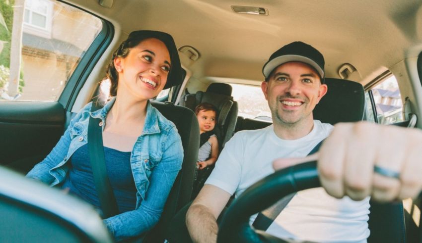 A man and woman are driving a car with a child in the back seat.