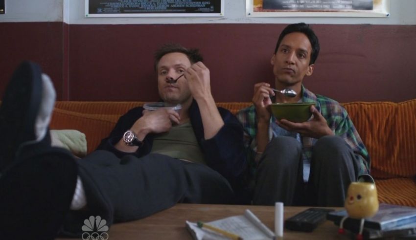 Two men sitting on a couch eating food.