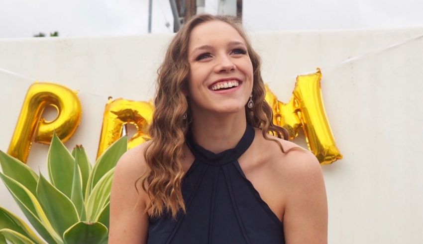 A woman smiling in front of a sign.
