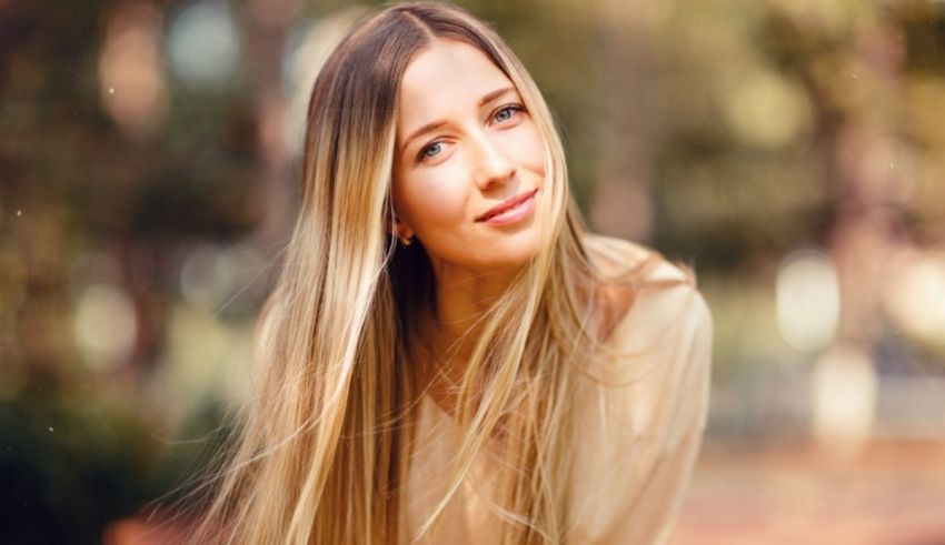 A woman with long blonde hair is sitting in a park.