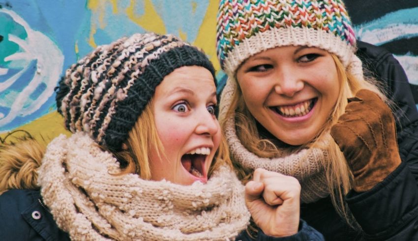 Two women wearing knit hats and scarves.