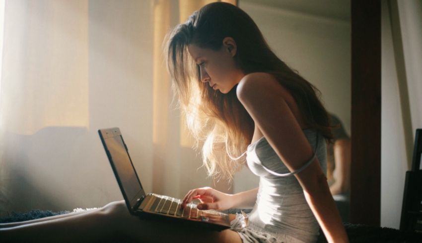 A girl sitting on a bed with a laptop.