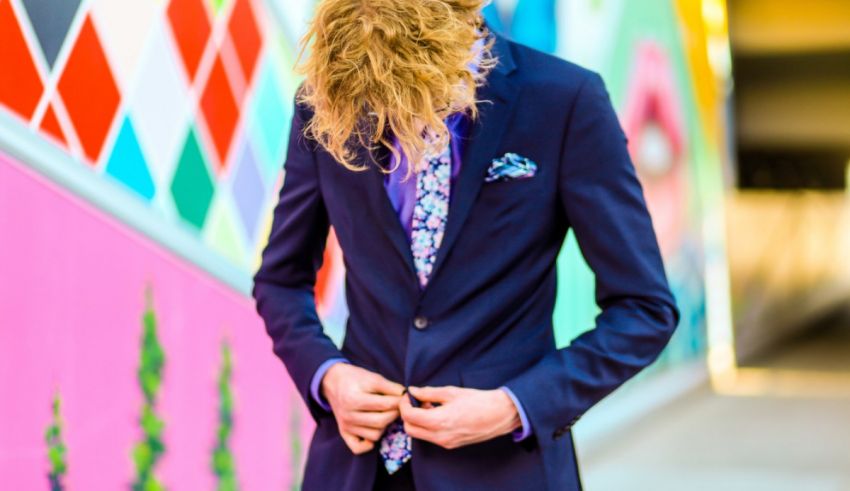 A young man in a suit and tie standing in front of a colorful wall.