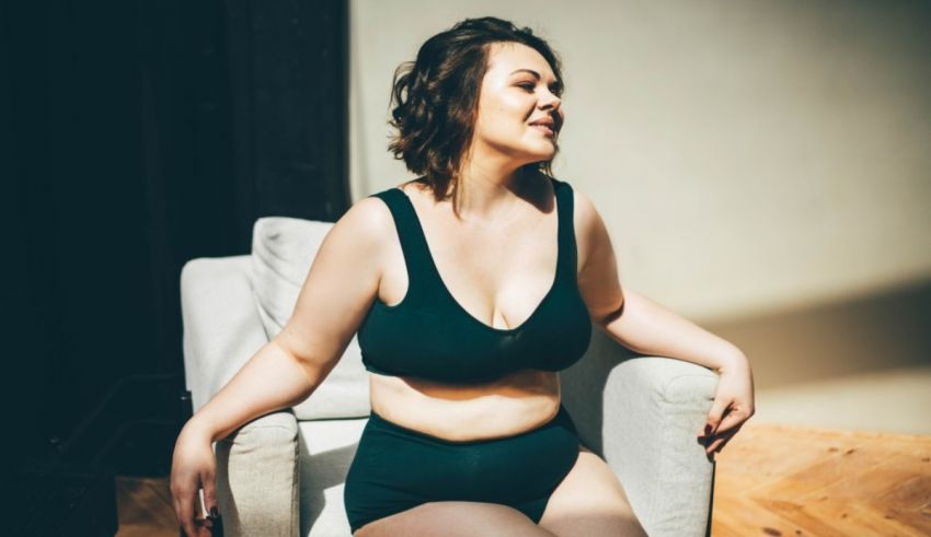 A woman sitting on a chair in a black bra.