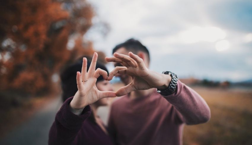A man and woman making a heart with their hands.