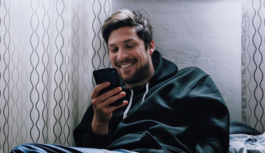 A man smiling while looking at his phone.