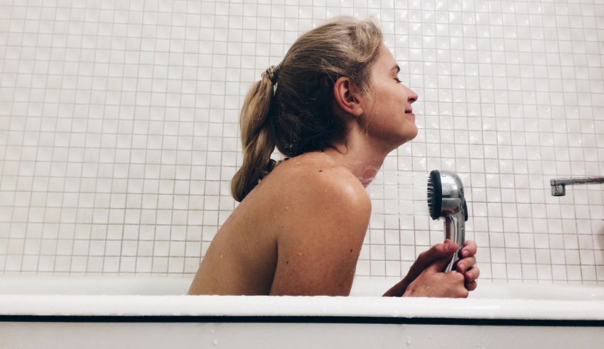 A woman is sitting in a bathtub with a hairdryer.