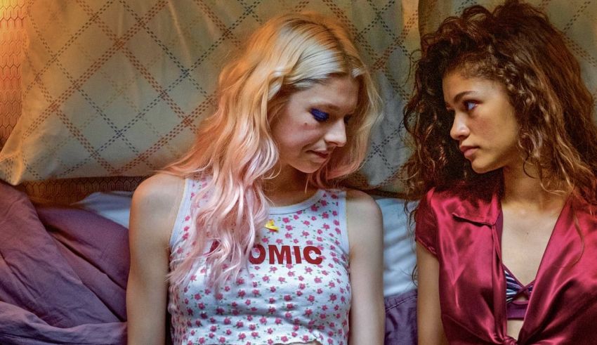 Two women sitting on a bed looking at each other.